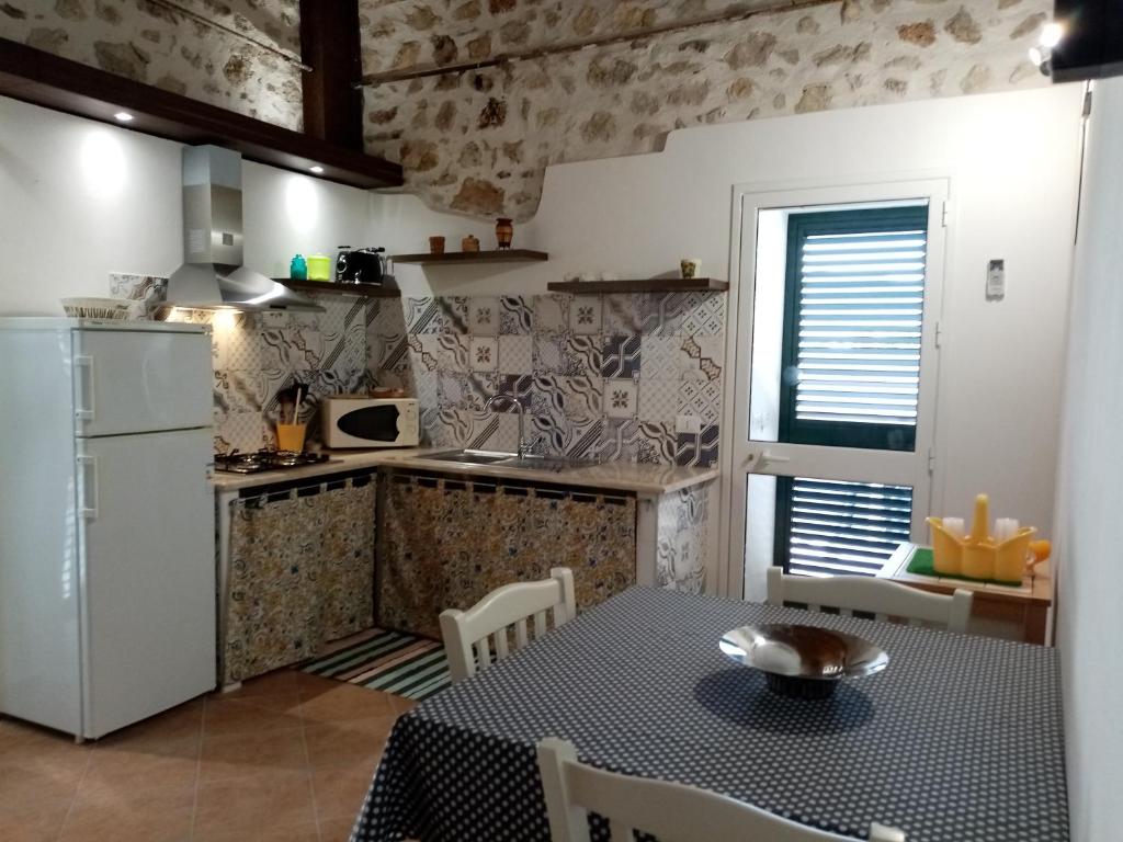 eine Küche mit einem Tisch und einem Kühlschrank sowie einem Tisch und Stühlen in der Unterkunft Casa vacanze Krimisòs in Castellammare del Golfo