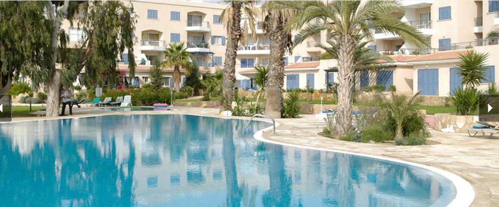 una gran piscina con palmeras y un edificio en Modern and stylish 1 bedroom apartment in King's Palace en Paphos
