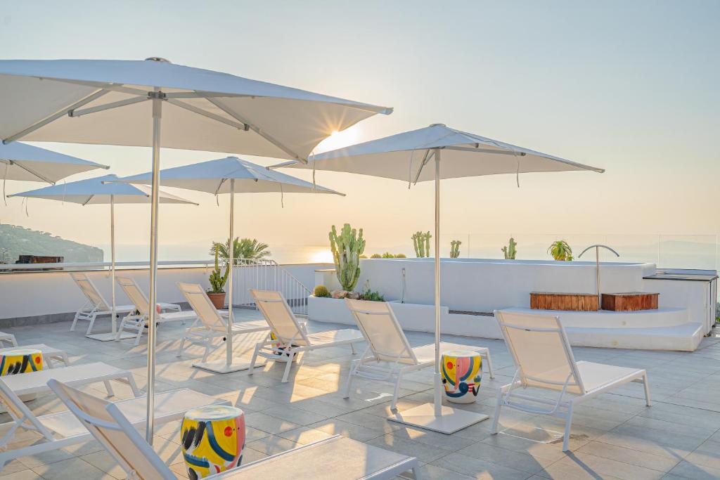 a patio area with chairs, tables and umbrellas at Domo 20 Hotel & Sky Bar in Vico Equense