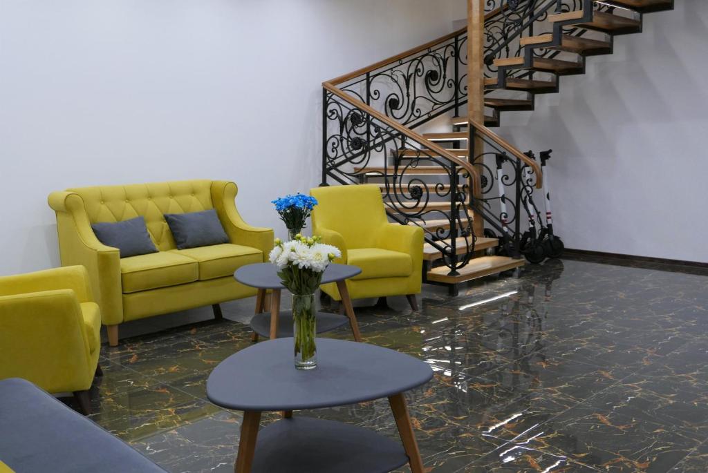 a lobby with yellow chairs and a vase of flowers on a table at Arch Apart Hotel in Yerevan
