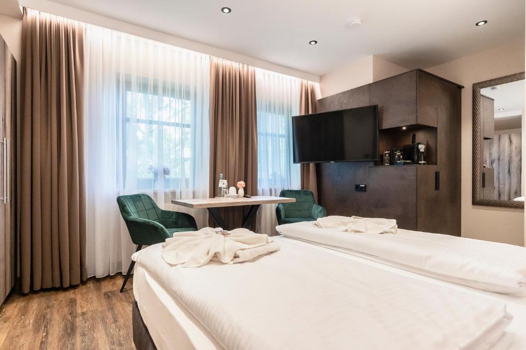 a hotel room with two beds and a table at Hotel Demas München-Unterhaching in Unterhaching