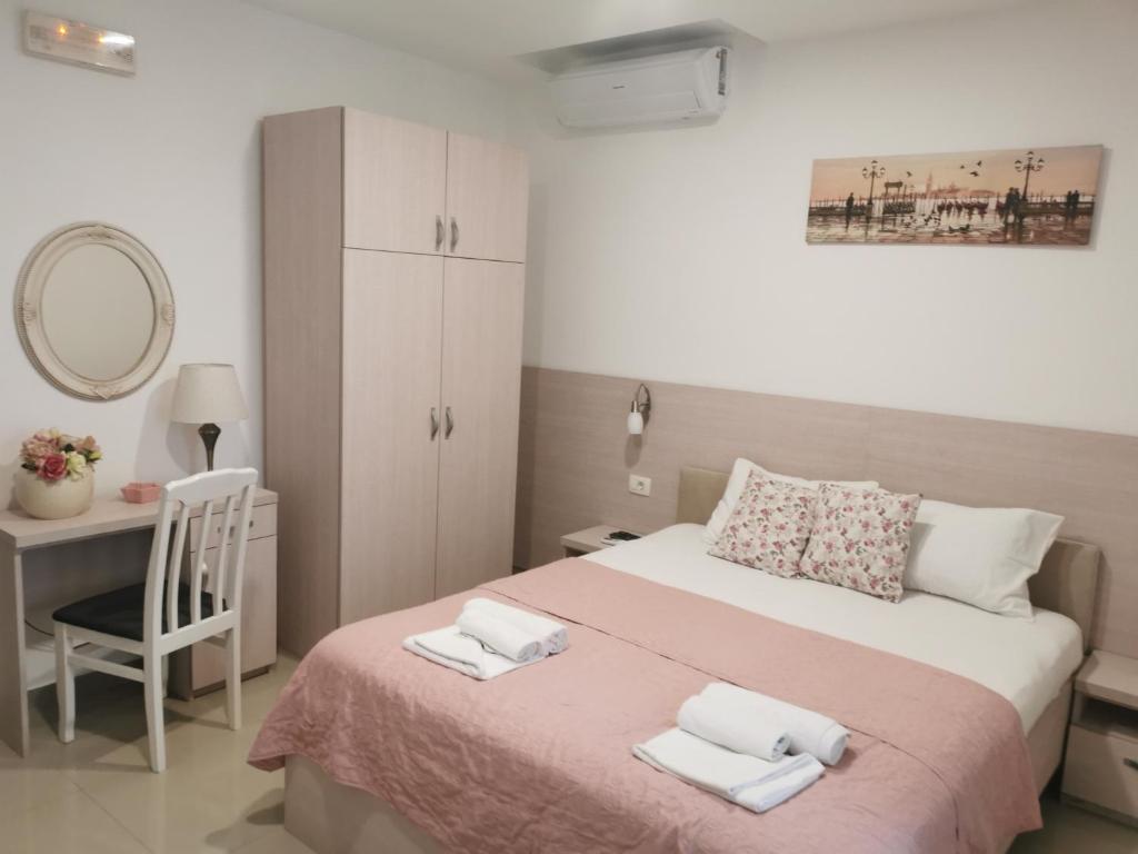 a bedroom with a bed with a desk and a mirror at Apartments Familia in Budva