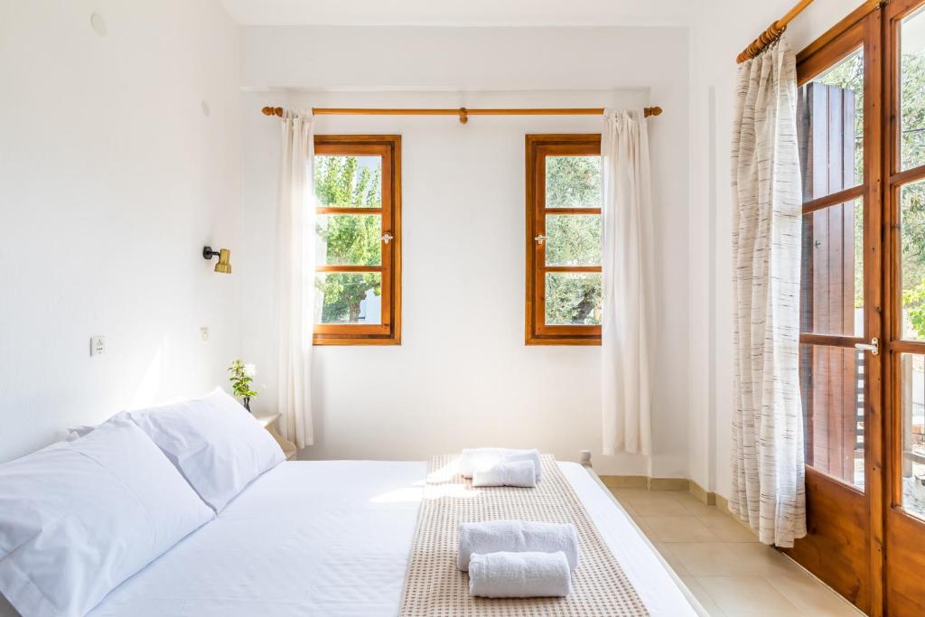 a white bedroom with a bed and two windows at Skopelos Evergreen Apartments in Stafylos