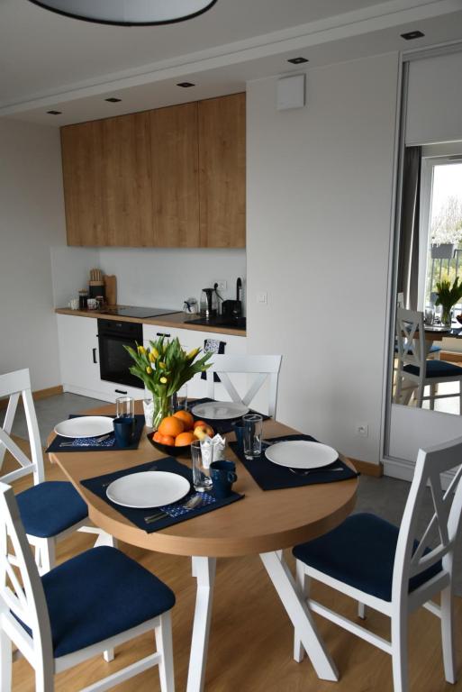 een eetkamer met een tafel en stoelen en een keuken bij Apartament Ahoj in Jastrzębia Góra