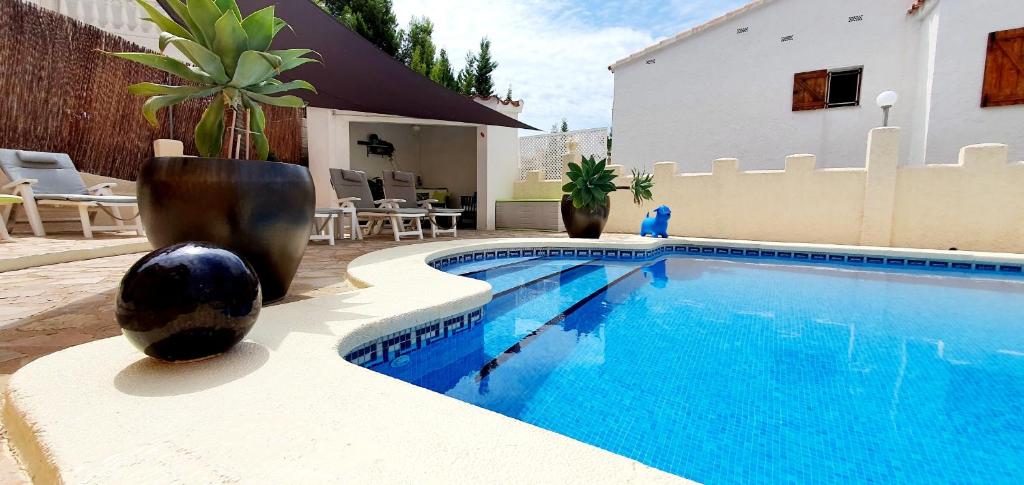 a swimming pool with two large vases next to a house at EL Gecko in Alcossebre