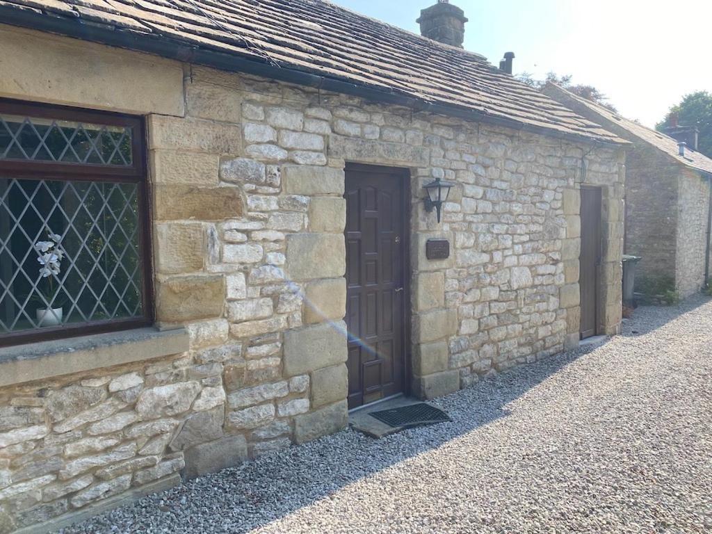 a stone building with a door and a window at Peveril Cottage in Castleton