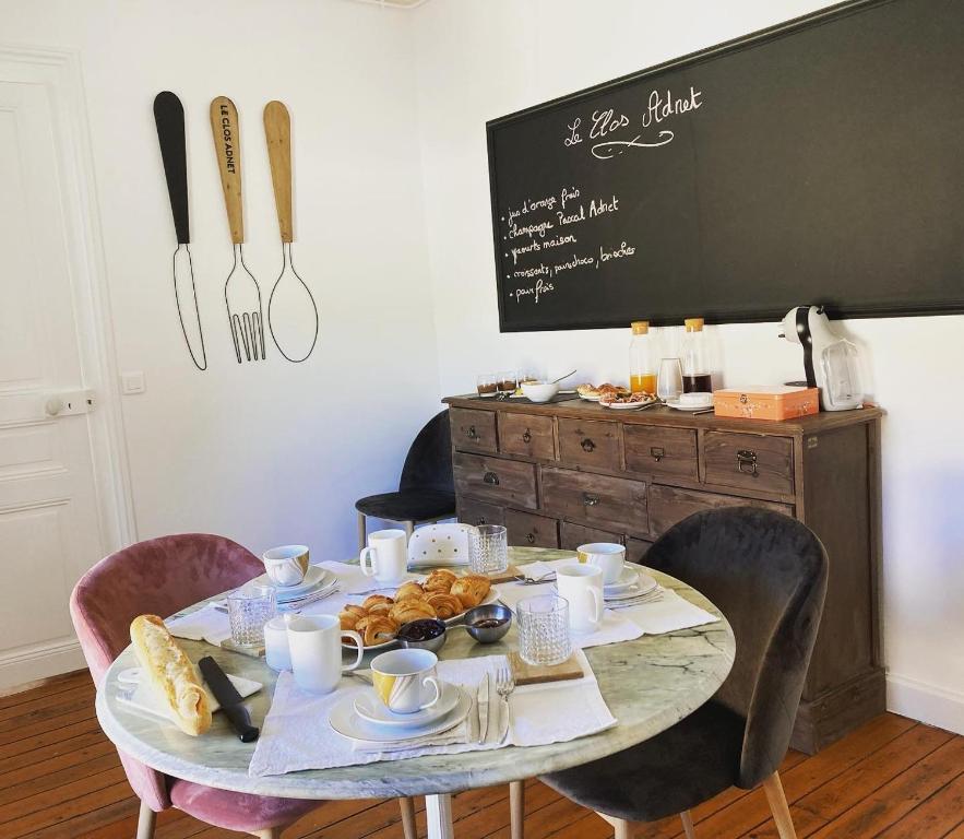 uma mesa com comida com cadeiras e um quadro-negro em Le Clos Adnet em Villers-Marmery