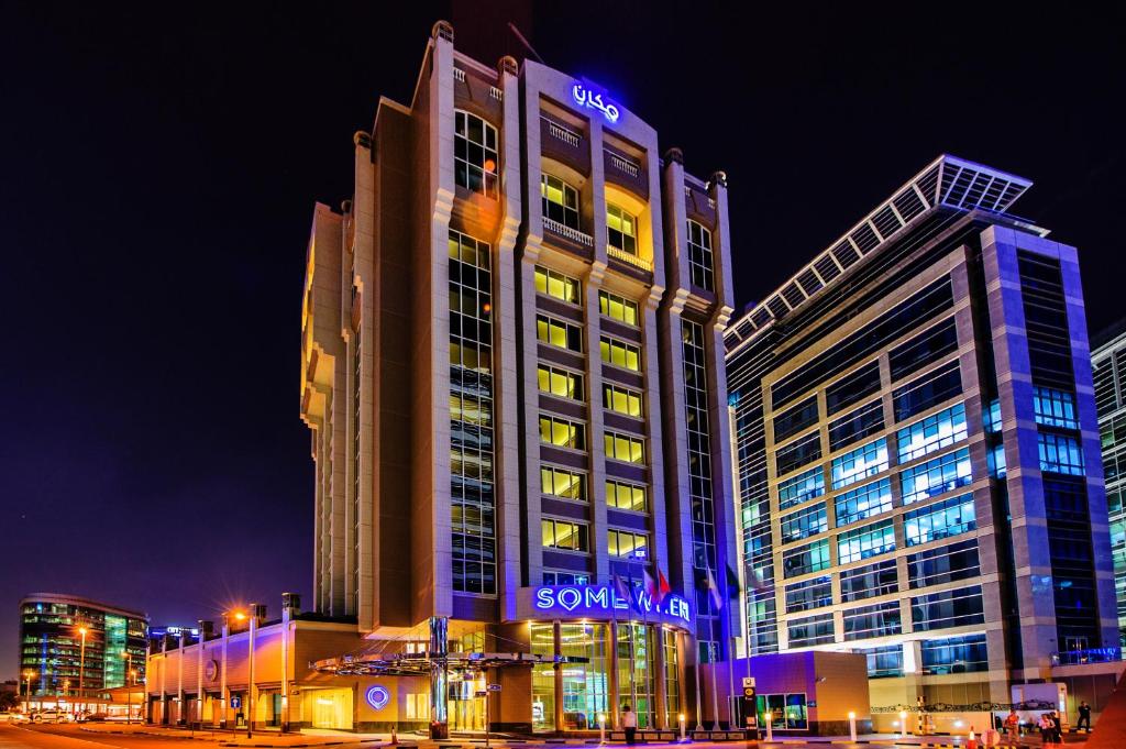 a large building with a sign on it at night at Somewhere Hotel Apartment in Dubai