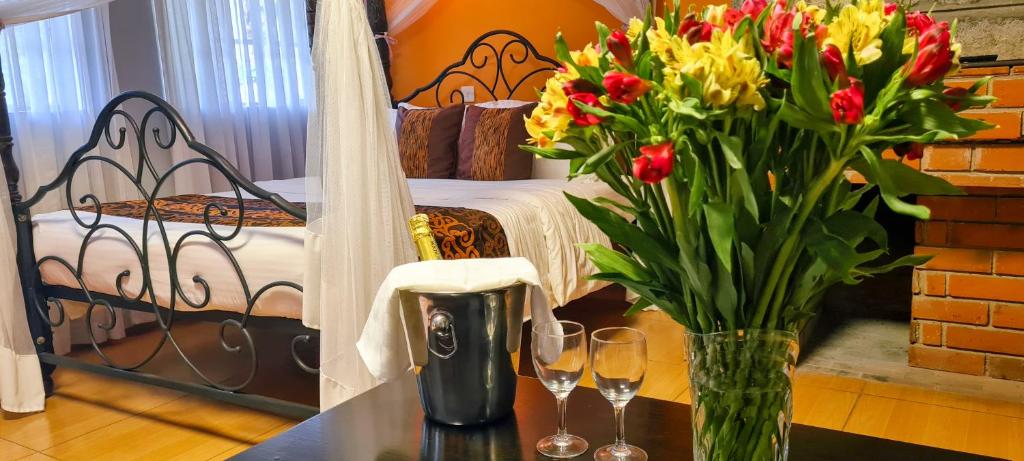 a vase of flowers on a table with wine glasses at Margarita House in Nairobi