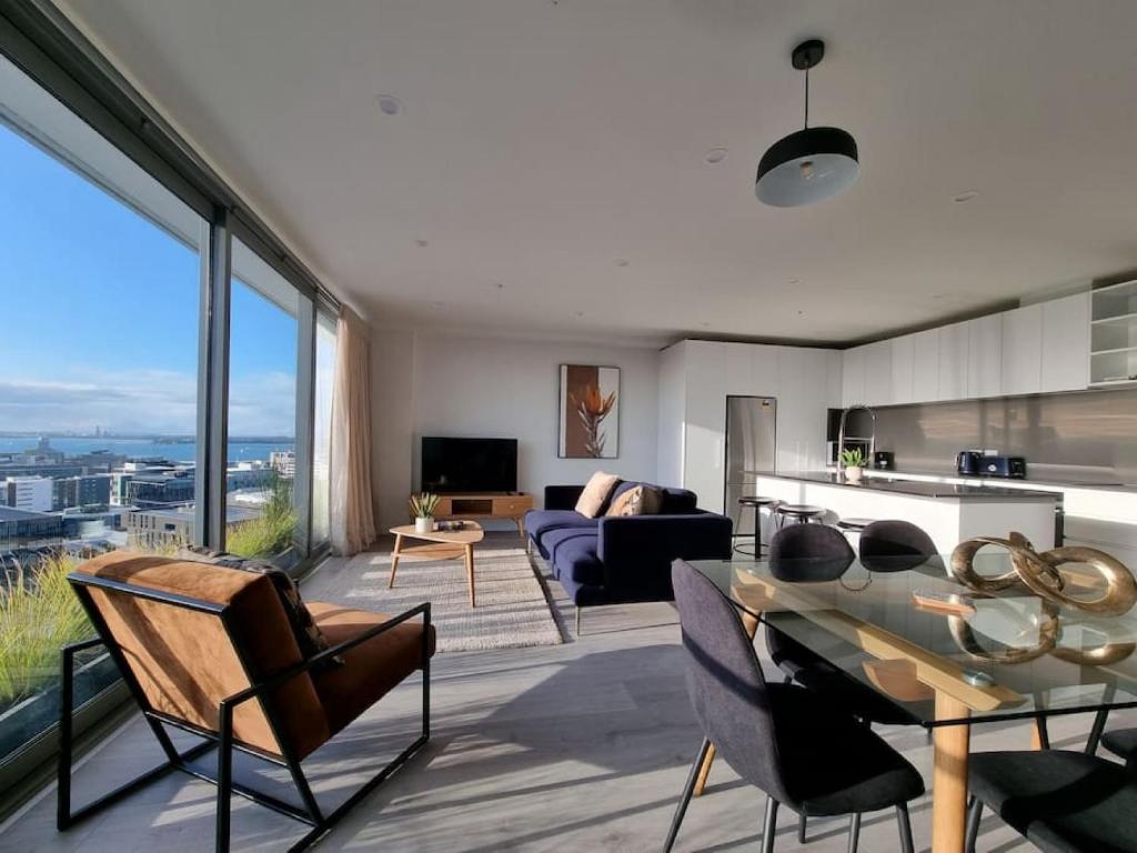 a living room with a couch and a table and chairs at Union Green Apt w Stunning Views - Free Parking in Auckland