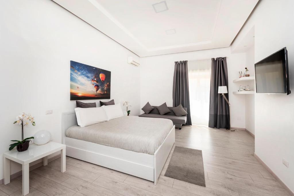 een witte slaapkamer met een bed en een bank bij Maison Piazza Cavour in Rome