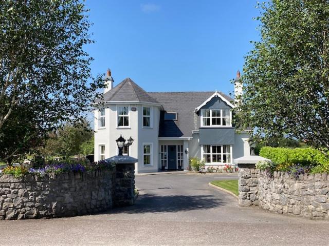 a large white house with a stone wall at Tailors Lodge, Luxurious peaceful Apartment- Castleisland, Kerry in Castleisland