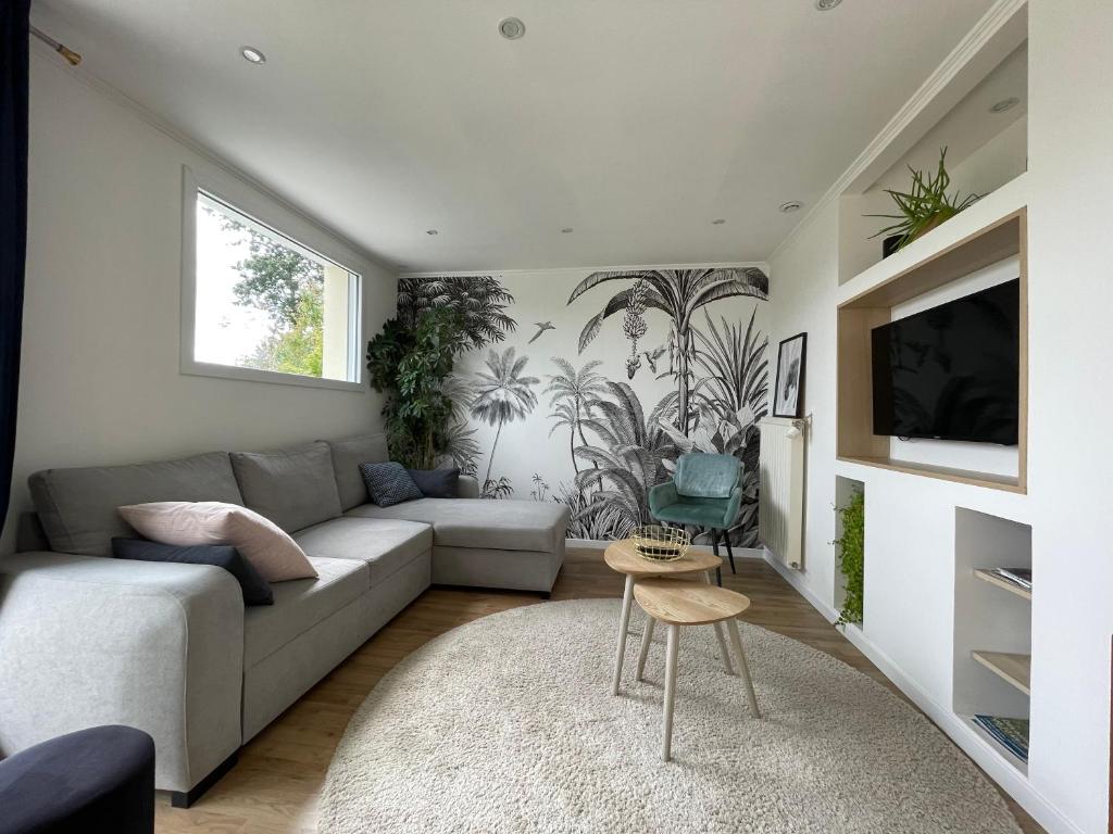 sala de estar con sofá y TV en Les sapins verts -inspiration deluxe en Saint-Lô