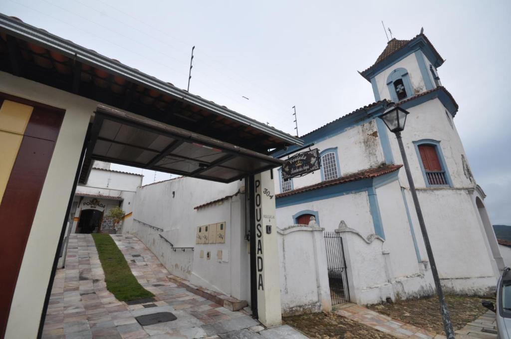 un edificio blanco con puerta y torre en Pousada Rainha dos Anjos, en Mariana