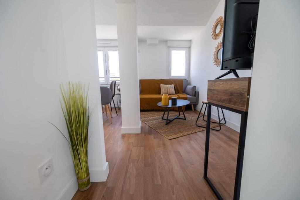 a living room with a couch and a table and a television at Le Poulorio 12 - T2 - Proche Gare - dernier étage By Locly in Lorient