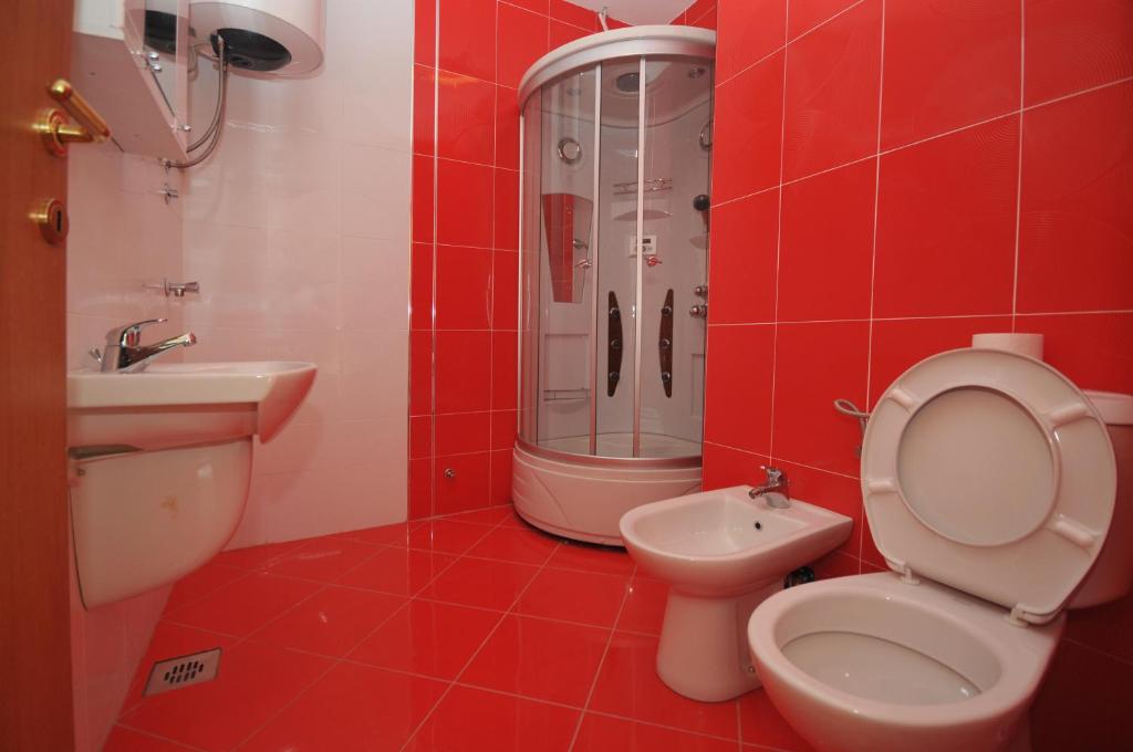 baño de azulejos rojos con aseo y lavamanos en Apartman Bravo Budva, en Budva