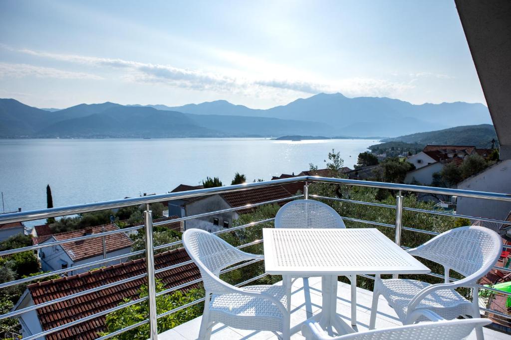 einen Tisch und Stühle auf einem Balkon mit Seeblick in der Unterkunft Boka 2 in Krasići