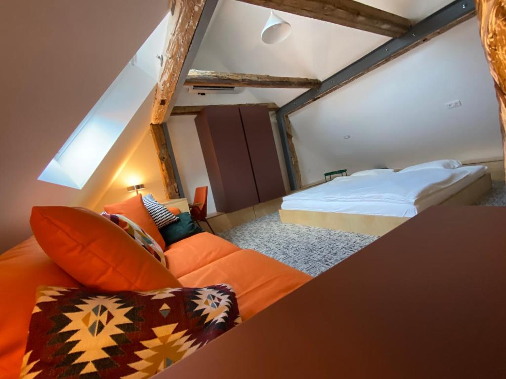 a bedroom with an orange couch and a bed at Isabella Living in Maribor
