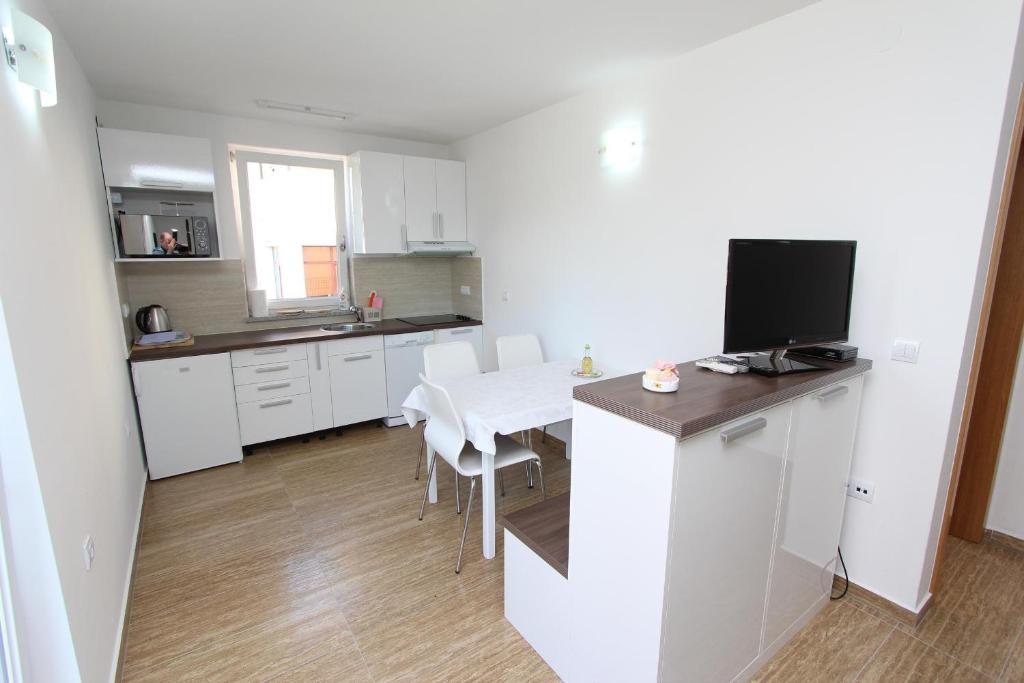 eine weiße Küche mit einem Tisch und einem TV in der Unterkunft Apartments Hanna in Rovinj