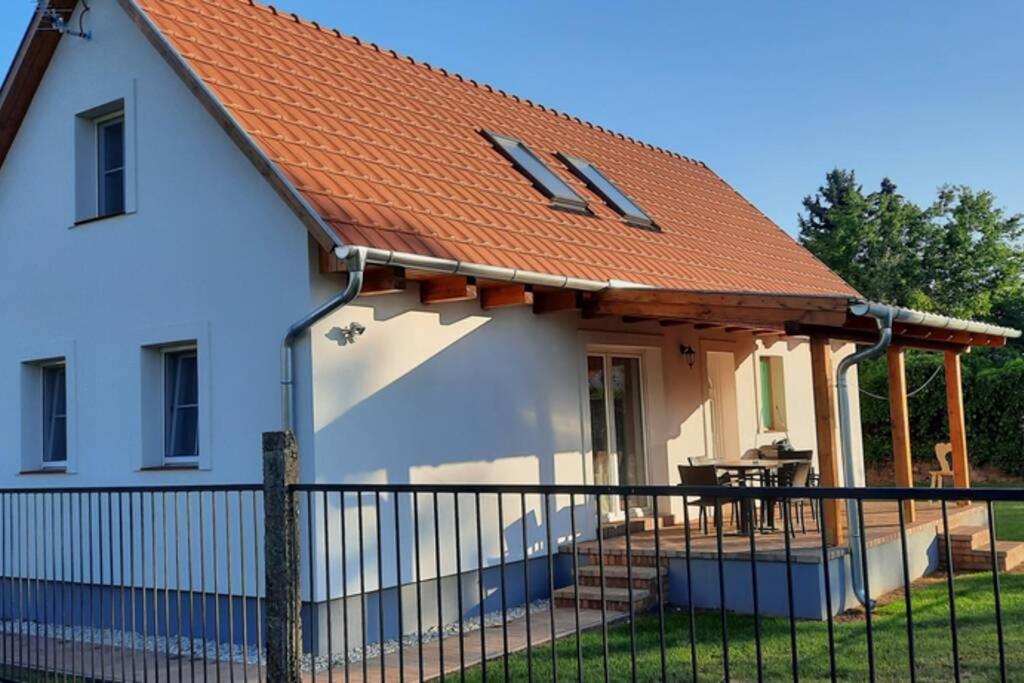 una casa con techo naranja y valla en Andrea nyaralóház, en Kővágóörs