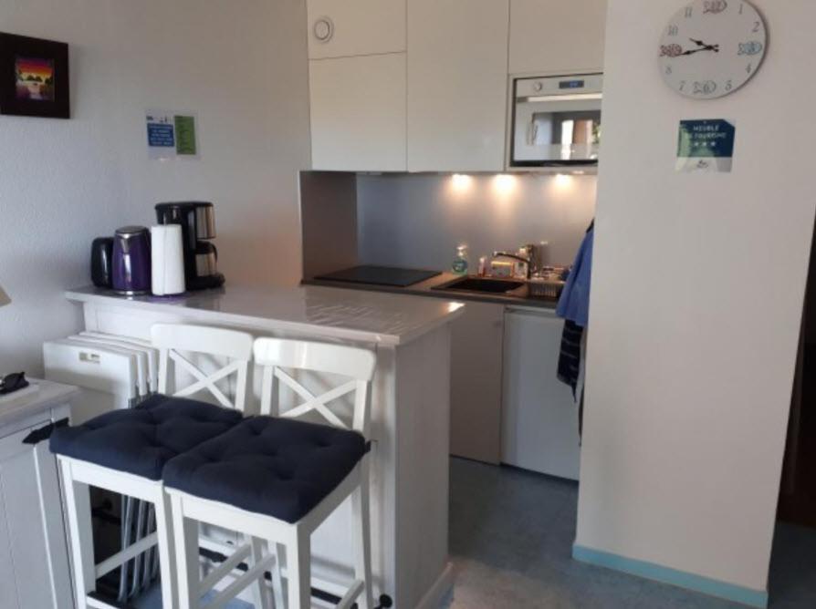 una cocina con 2 taburetes y una barra en CLAIRE MARINE PORNIC, en Pornic