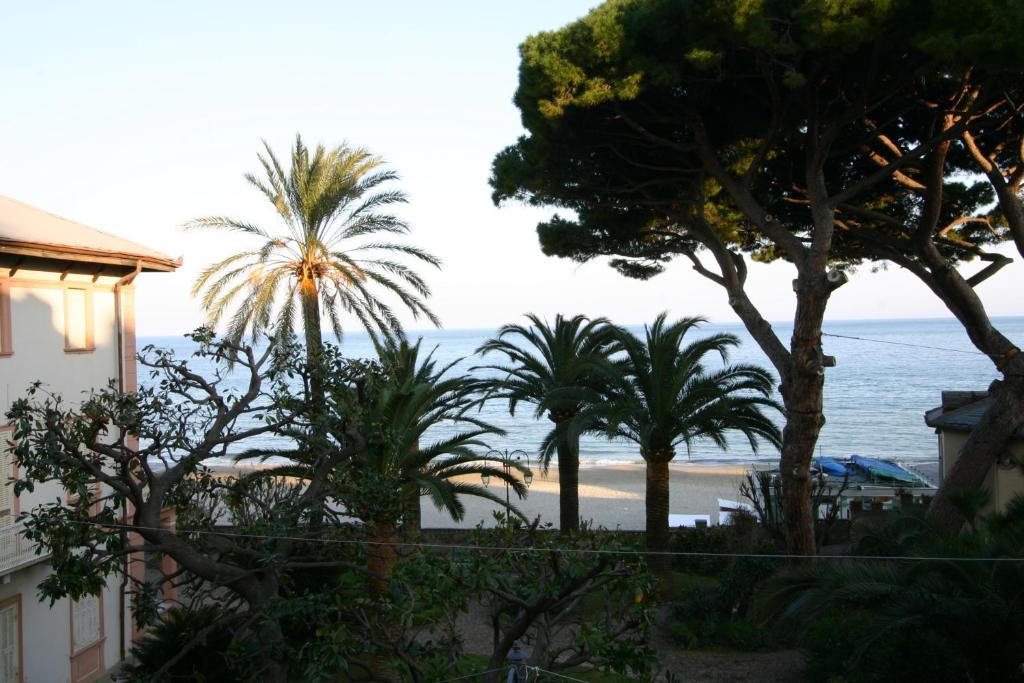 アラッシオにあるResidence Principi di Piemonteのヤシの木が植わる家から海岸を望む