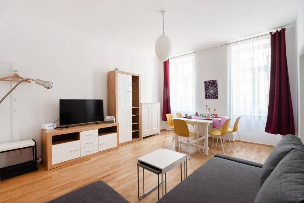 ein Wohnzimmer mit einem Sofa und einem Tisch mit Stühlen in der Unterkunft Vienna Living Apartments - Raffaelgasse in Wien
