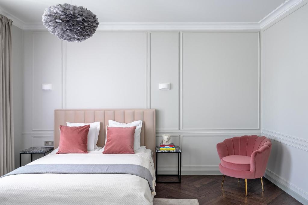 um quarto com uma cama e uma cadeira rosa em Place No. 2 em Vilnius