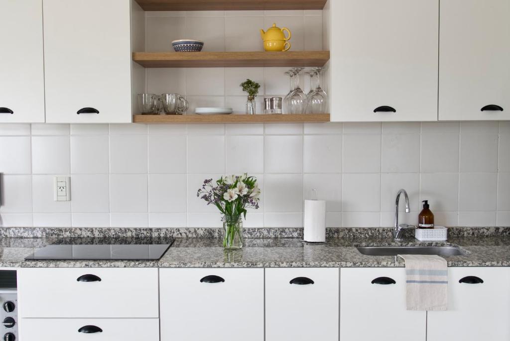 a kitchen with white cabinets and a vase of flowers at Las Cumbres Ushuaia in Ushuaia
