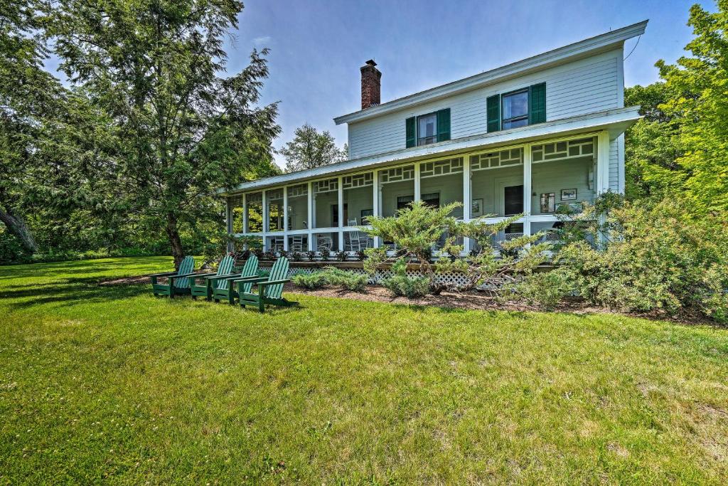 a large white house with green chairs in the yard at Waterfront Schroon Lake Home with Boat Dock! in Schroon Lake