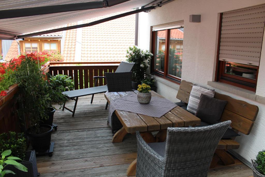 un patio con una mesa de madera y sillas en una terraza en Ferienwohnung Forellenhof, en Oberschwarzach