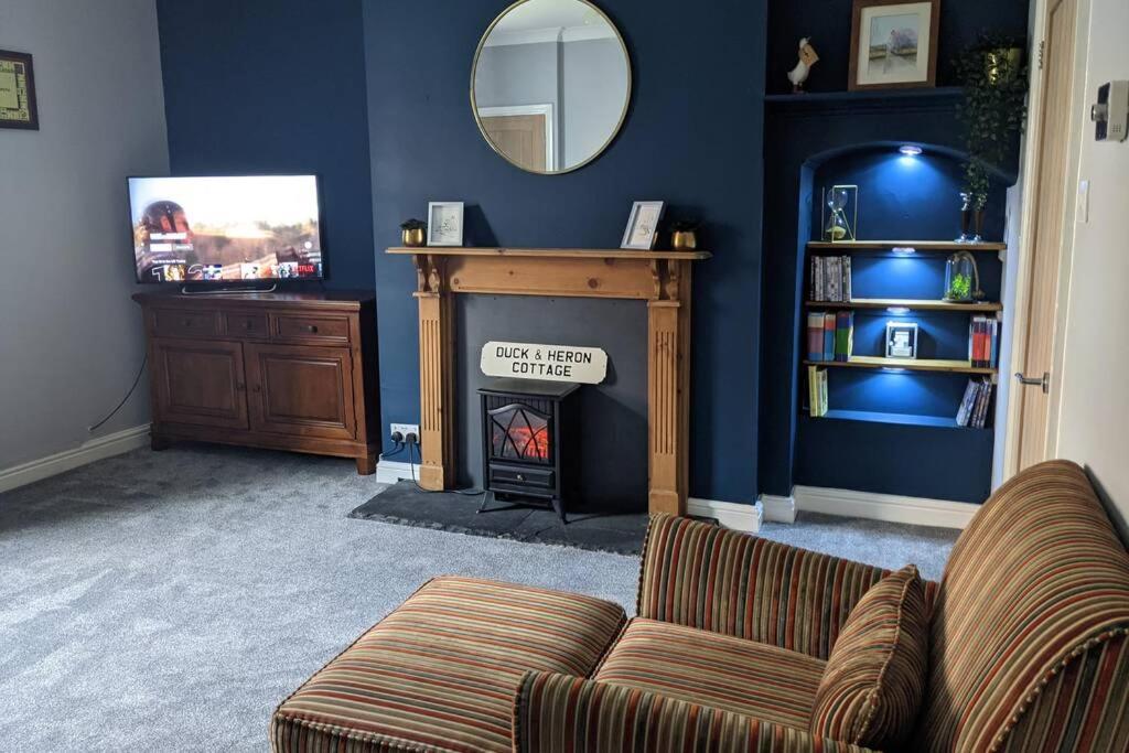 a living room with a couch and a fireplace at Duck & Heron Cottage in Morpeth