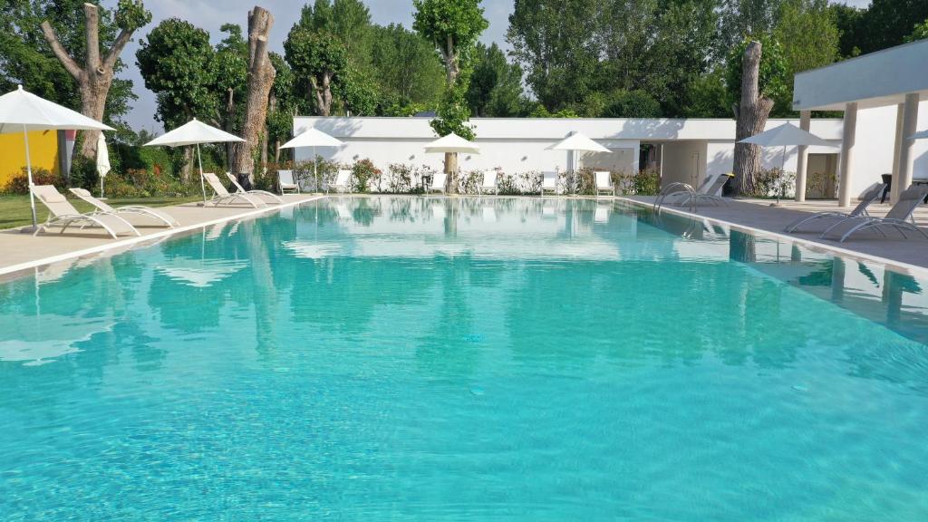 a large blue swimming pool with chairs and umbrellas at Camping Rialto in Campalto