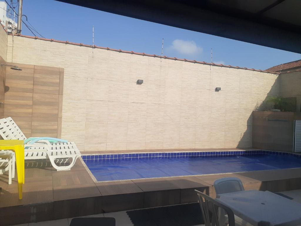 uma pequena piscina com mesa e cadeiras em casa com piscina aquecida e churrasqueira em Praia Grande na Praia Grande