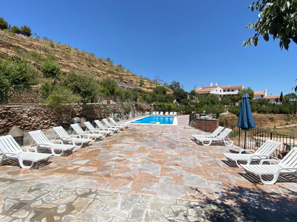 a group of lounge chairs and a swimming pool at Reul Alto Cortijos Rurales in Laroya
