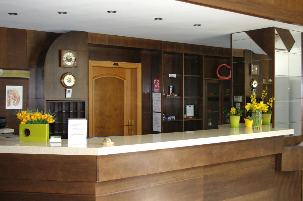 a lobby of a hotel with a counter and flowers at Hotel Širák in Most