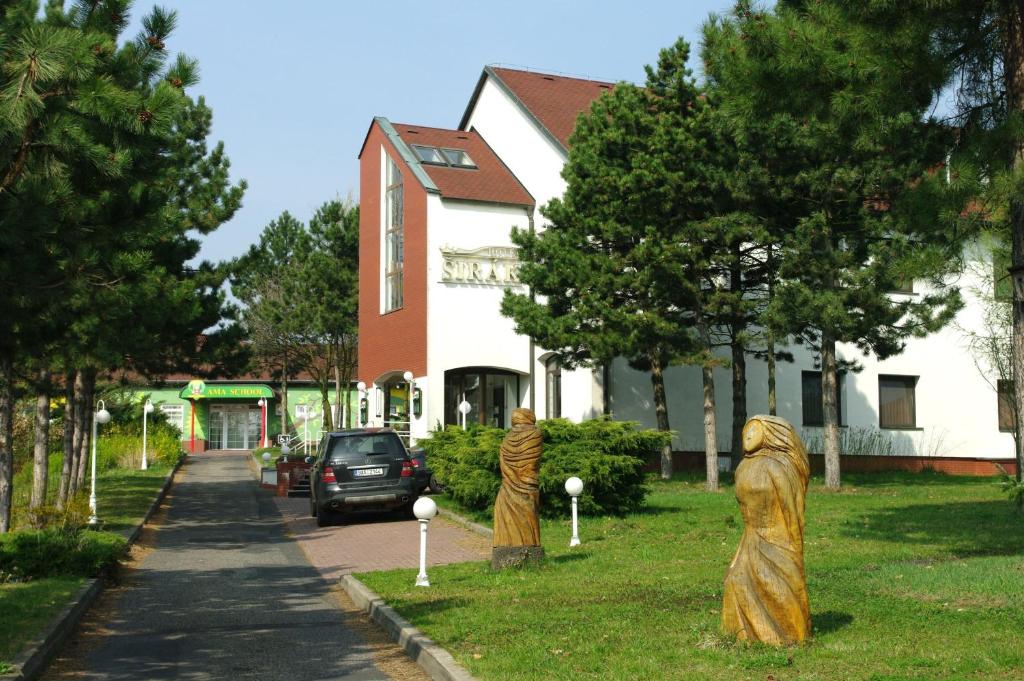 Deux statues de gens dans l'herbe devant une maison dans l'établissement Hotel Širák, à Most