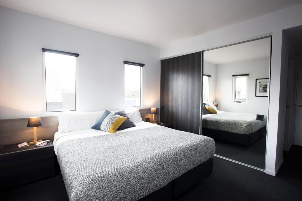 um quarto de hotel com duas camas e um espelho em Tyrian Serviced Apartments Fitzroy em Melbourne