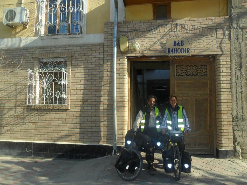 Deux hommes sont assis sur des motos devant un bâtiment dans l'établissement B&B Bahodir, à Samarcande
