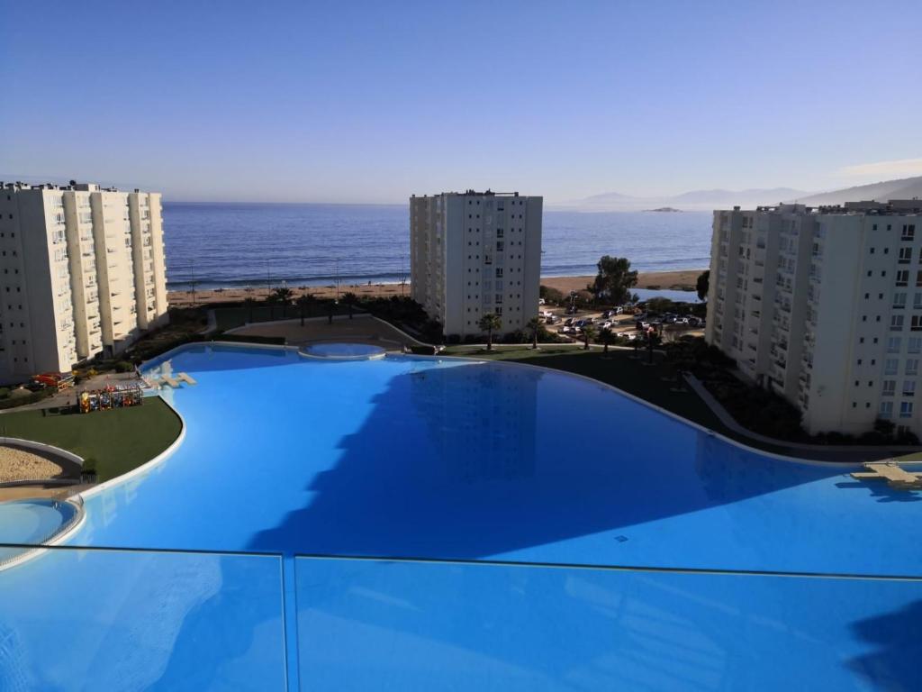 een groot blauw zwembad voor sommige gebouwen bij Departamento Papudo Laguna in Papudo