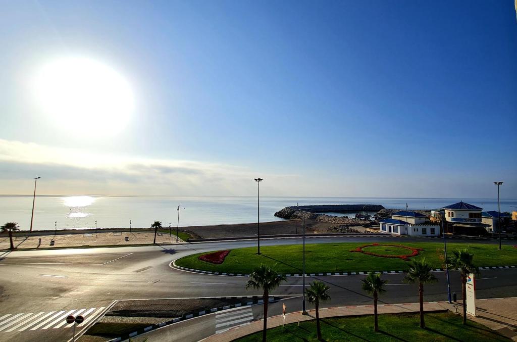 um parque de estacionamento vazio junto ao oceano com palmeiras em Hotel La Corniche Fnideq em Fnideq