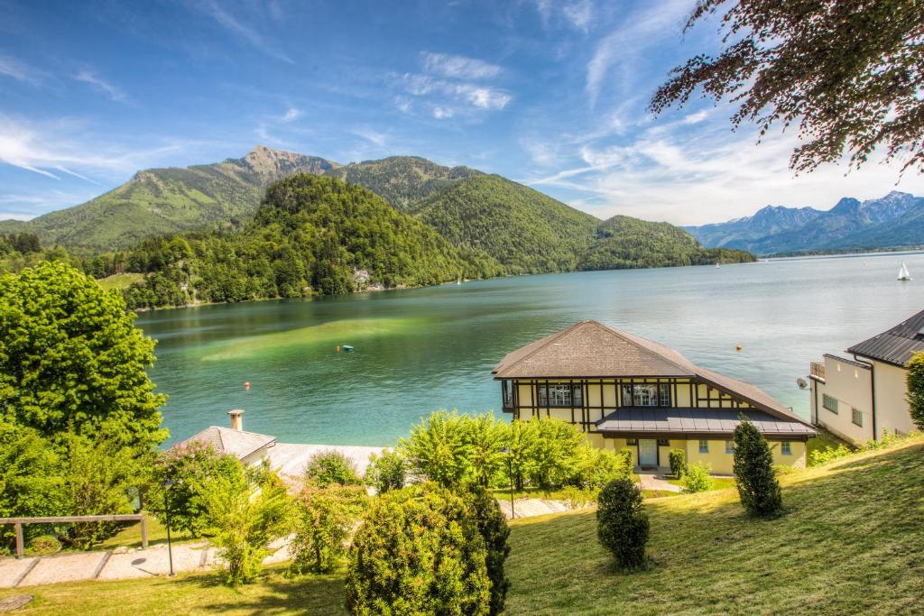 una casa a orillas de un lago con montañas en Seehotel Billroth, en Sankt Gilgen