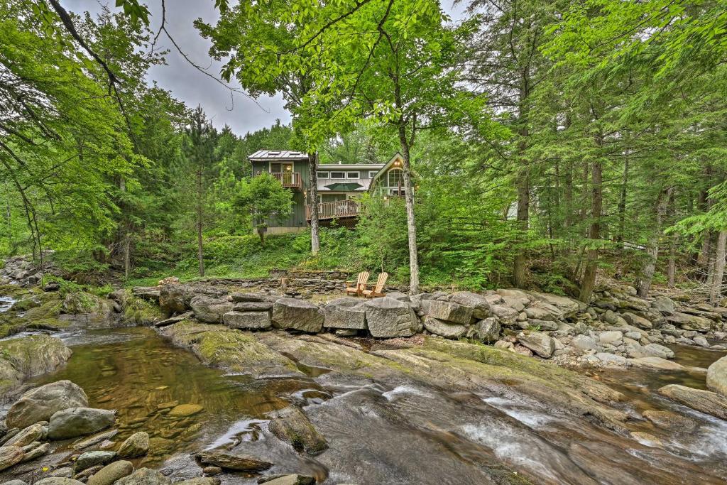 a house in the woods next to a river at Beautiful Jay Peak Home Near Creek and Waterfalls! in Jay