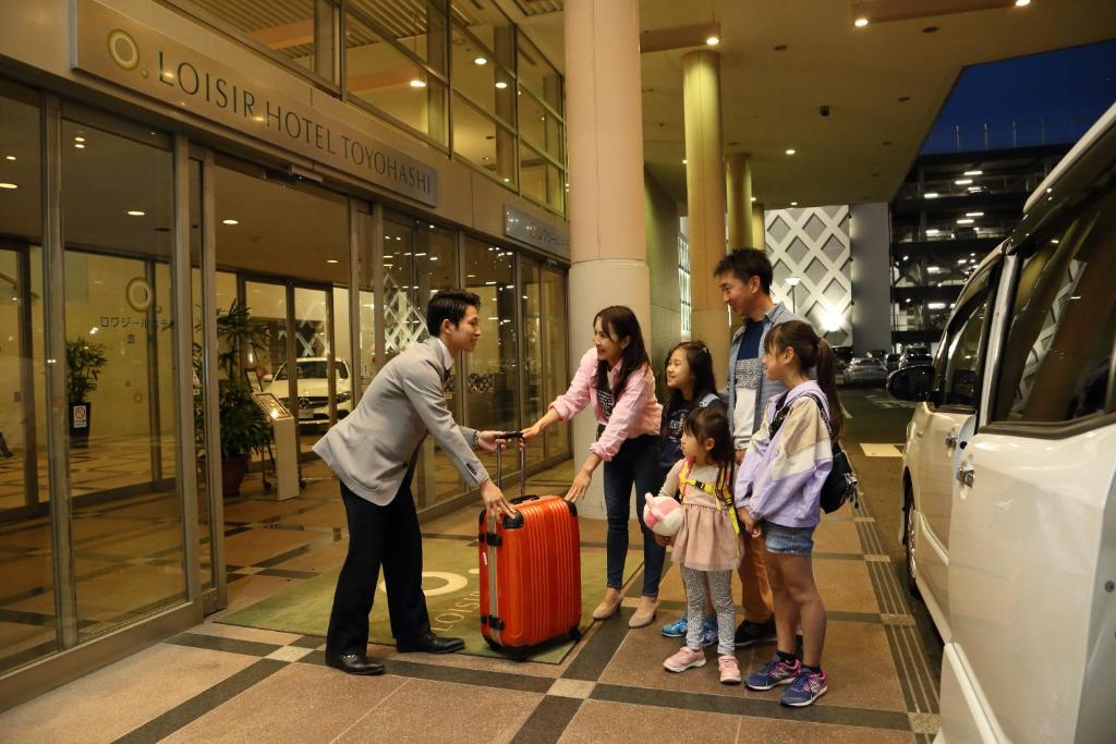 un grupo de gente dándose la mano delante de una tienda en Loisir Hotel Toyohashi en Toyohashi