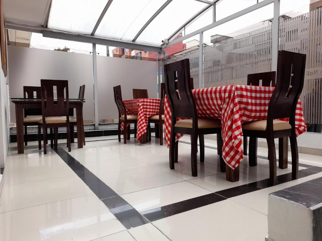 un comedor con mesas y sillas rojas y blancas a cuadros en Embassy On Holidays, en Bogotá