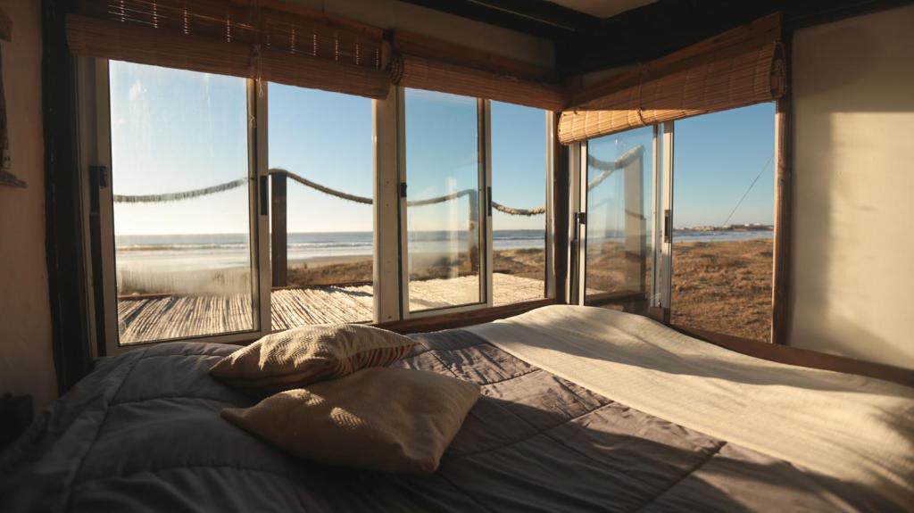 een slaapkamer met een bed en uitzicht op het strand bij Ventanas al Mar in Cabo Polonio