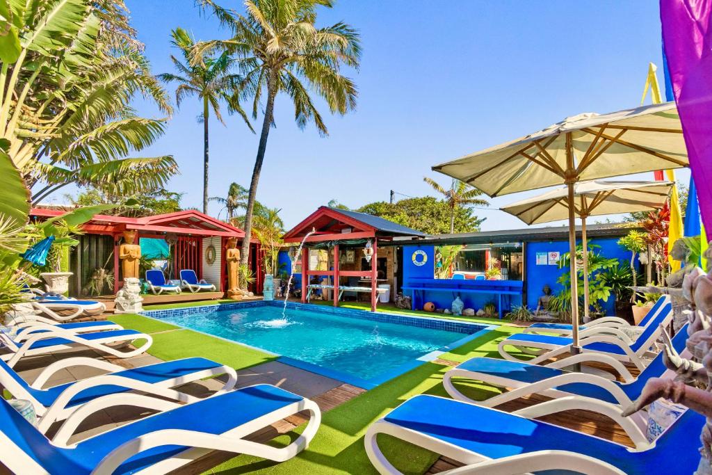 a beach area with chairs, tables, and umbrellas at Hideaway Noosa Men Only Beach Resort in Peregian Beach