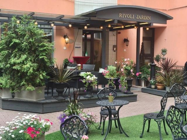 
a patio area with tables, chairs and umbrellas at Hotel Rivoli Jardin in Helsinki
