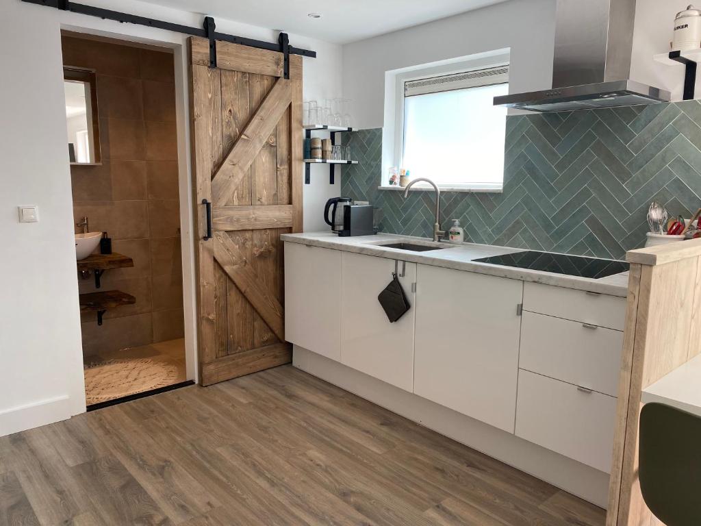 una cocina con fregadero y una puerta corredera de granero en The Forester Schoorl en Schoorl