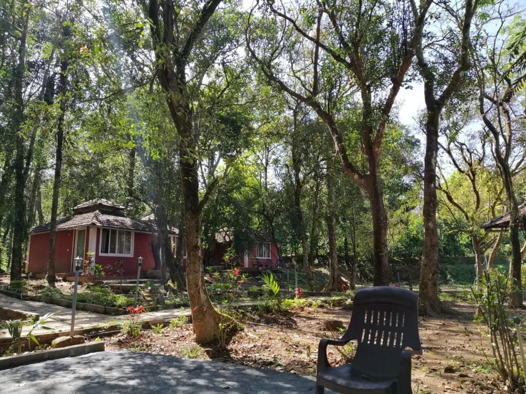 un banco sentado frente a una pequeña casa roja en Vamoose Friendz Homestay, en Sakleshpur